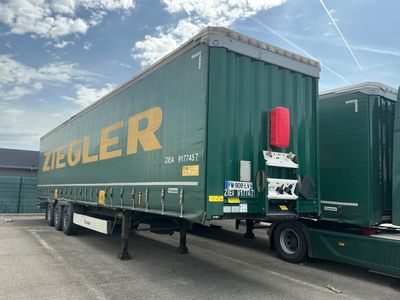 un semi-remorque vert garé sur un parking