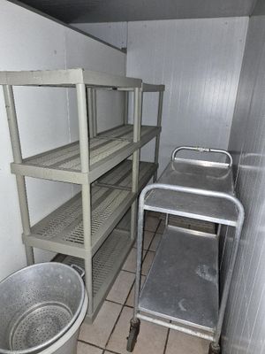 une petite pièce avec une étagère en métal et un seau en métal