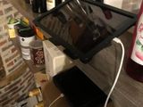 a tablet on a shelf next to bottles of wine and bottles of wine