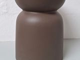 un vase marron posé sur une table blanche