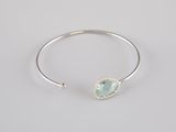 a close up of a silver bang bracelet with a green stone on it