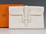 une photo d'un sac à main blanc posé sur une table, à côté d'une boîte orange