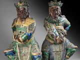 two chinese figurines of two men sitting on their knees