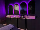 purple lights illuminate the walls of a room with a bed and a sink