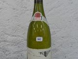 une bouteille de vin posée sur une table, avec un mur blanc en arrière-plan