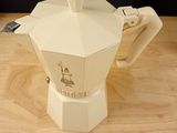 a small white coffee pot on a wooden table