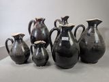cinq vases noirs posés les uns à côté des autres sur une table