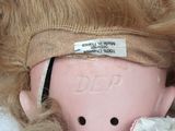 a doll with a blindfold on it ' s head laying on a bed
