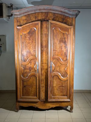 a large wooden armoire in a room with tile flooring
