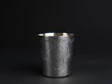 a close up of a silver cup on a black surface