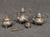 trois théières en argent et une théière posées sur une table