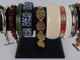 many different bracelets on display on a black stand