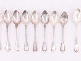 six silver spoons are lined up in a row on a white surface