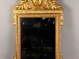 un miroir avec un cadre doré sur un mur blanc