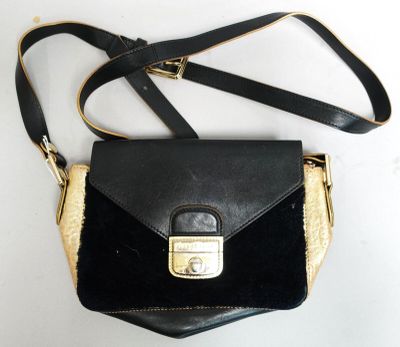 un sac à main noir avec une poignée dorée posé sur une table blanche