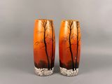 une paire de vases orange ornés d'arbres sur fond gris