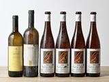 six bouteilles de vin sont alignées sur une table en bois