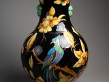 un vase noir sur lequel sont peints un oiseau et des fleurs