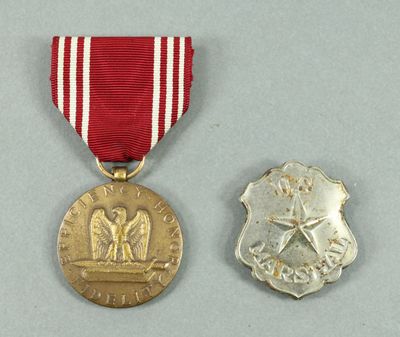two medals with a red ribbon and a silver medal on a gray surface