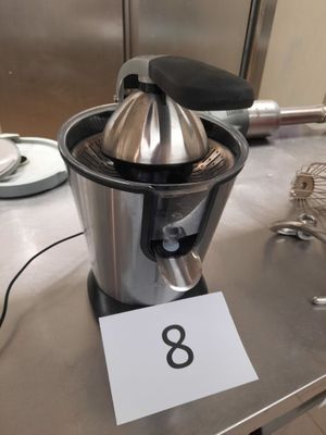 un presse-agrumes en argent posé sur une table sur laquelle figure le chiffre 8