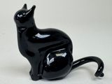 a black cat figurine sitting on a white surface