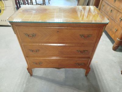 une commode en bois avec un plateau en verre dans une pièce