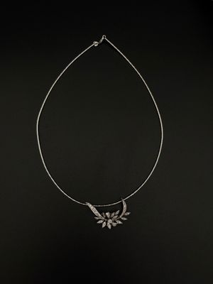 un collier en argent sur fond noir, orné d'un oiseau