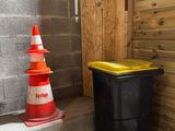 une poubelle noire posée à côté d'un cône jaune et blanc
