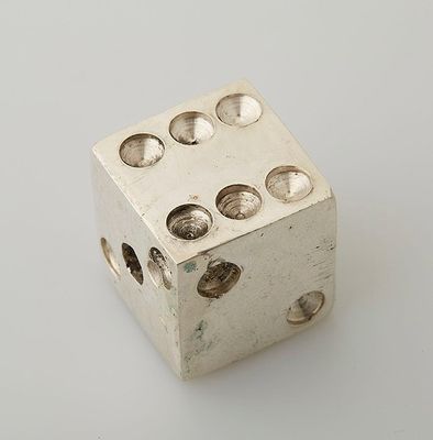 a silver dice with holes on it on a white surface