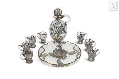un plateau en verre et en argent sur lequel sont posés une carafe en verre et des tasses