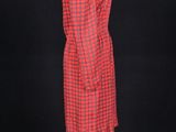 a red and black dress on a mannequin stand against a black background