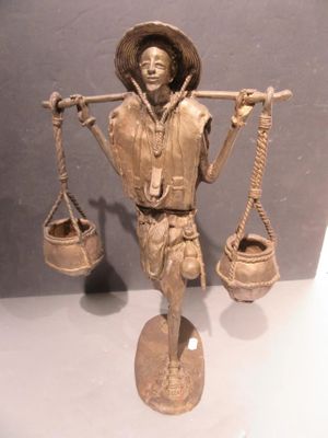 a bronze statue of a man holding a scale and a bucket