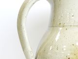 a white vase with a handle on a white surface