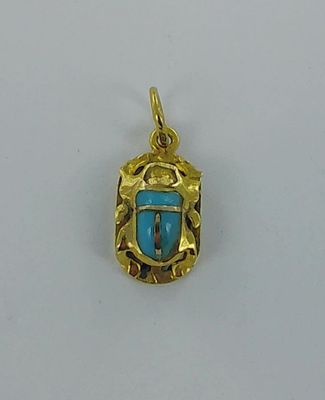 a close up of a gold pendant with a blue stone in the center