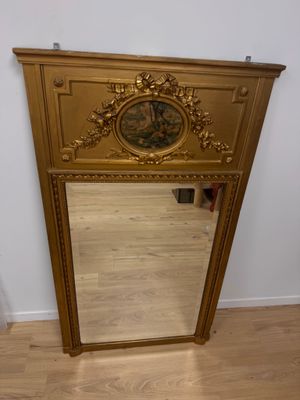 un miroir avec un cadre doré et une horloge dessus