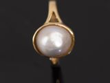a close up of a pearl ring on a black surface