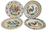 quatre assiettes de couleurs différentes, ornées de coqs et de fleurs
