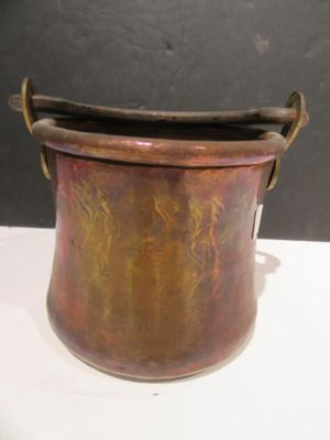 a small copper pot with a handle on a white table