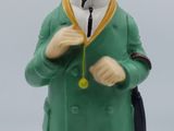 une figurine représentant un homme vêtu d'un manteau vert et d'un chapeau