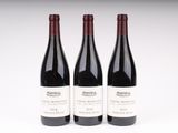 trois bouteilles de vin sont alignées sur une surface blanche