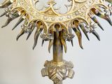 a gold sunburst on a stand with a clock on it