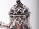 a silver tea pot with a bird on top of it