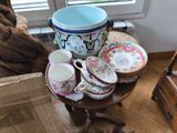 un chat assis sur une chaise à côté d'une table sur laquelle se trouvent des tasses et des soucoupes