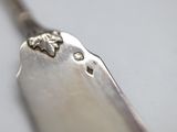 a silver spoon with a flower on it sitting on a table