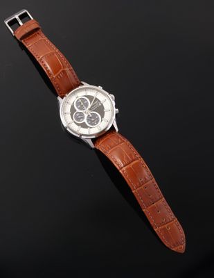 a close up of a watch on a black surface with a black background
