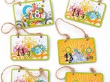 four tags with different designs hanging from strings on a white surface