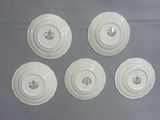 six white plates with designs on them on a gray surface