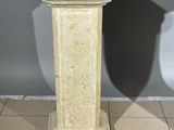 a stone pedestal on a tiled floor with a shadow on the wall