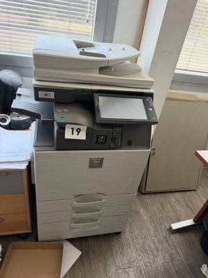 a printer sitting on top of a desk next to a chair