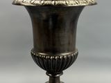 an antique silver vase on a wooden base on a gray background